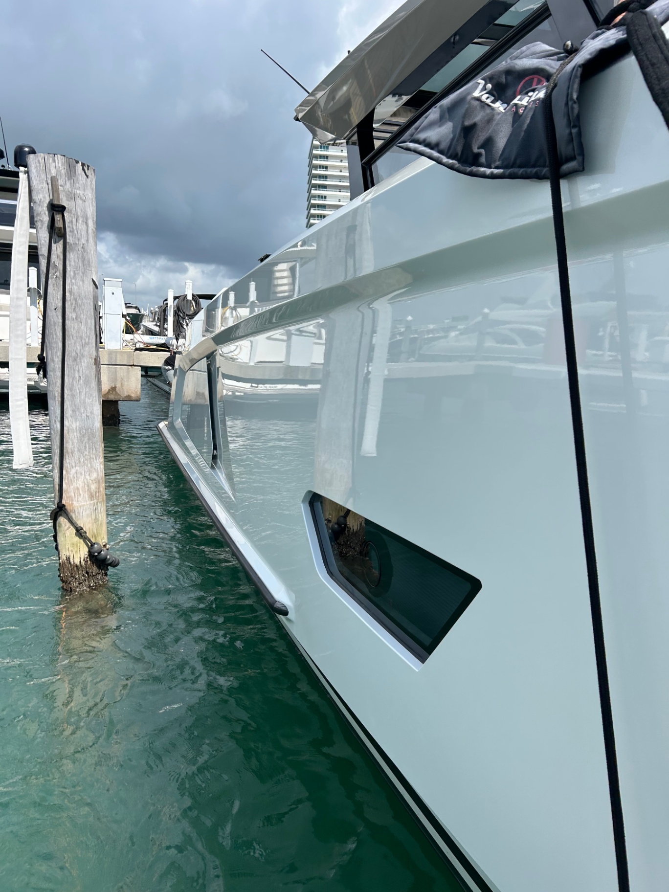 Vanquish yacht with glossy seafoam hull reflecting marina water