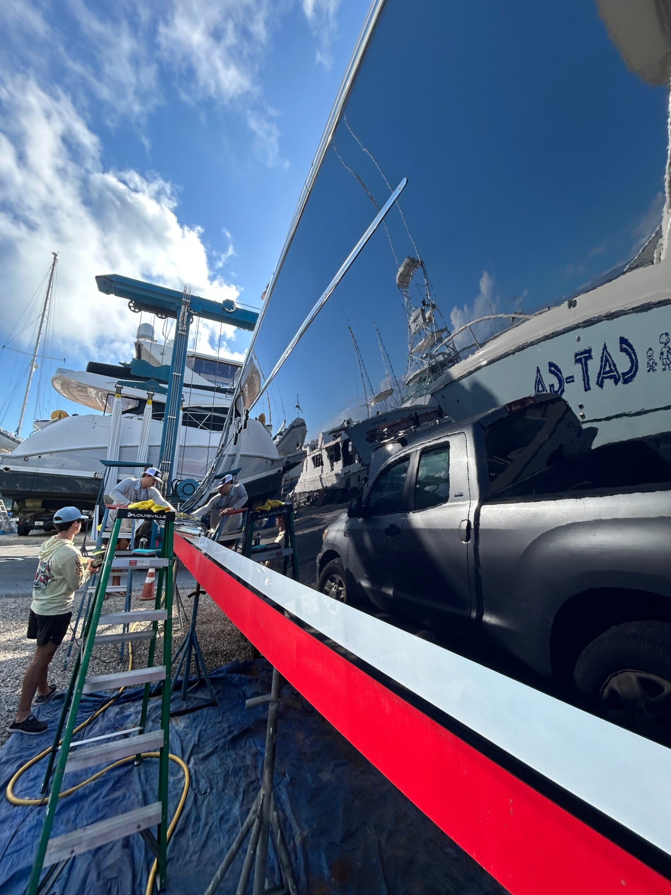 AC Detailing crew polishing a J Craft yacht hull at the boatyard